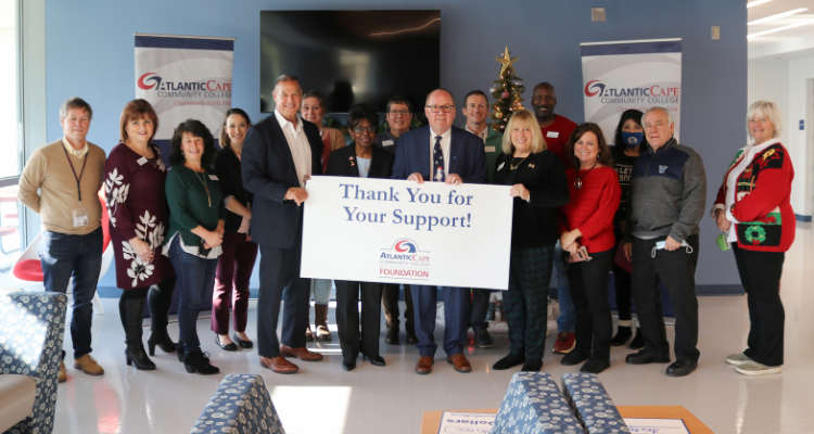 OceanFirst Foundation Board member Dr. Robert A. Previti, who is also a Trustee at Atlantic Cape Community College; Atlantic Cape President Dr. Barbara Gaba; Jeff Ropiecki, OceanFirst’s vice president of commercial lending; and Foundation Executive Director Jean McAlister, with staff from Atlantic Cape hold up a thank you sign for the donation at the Mays Landing campus on Dec. 22, 2021.